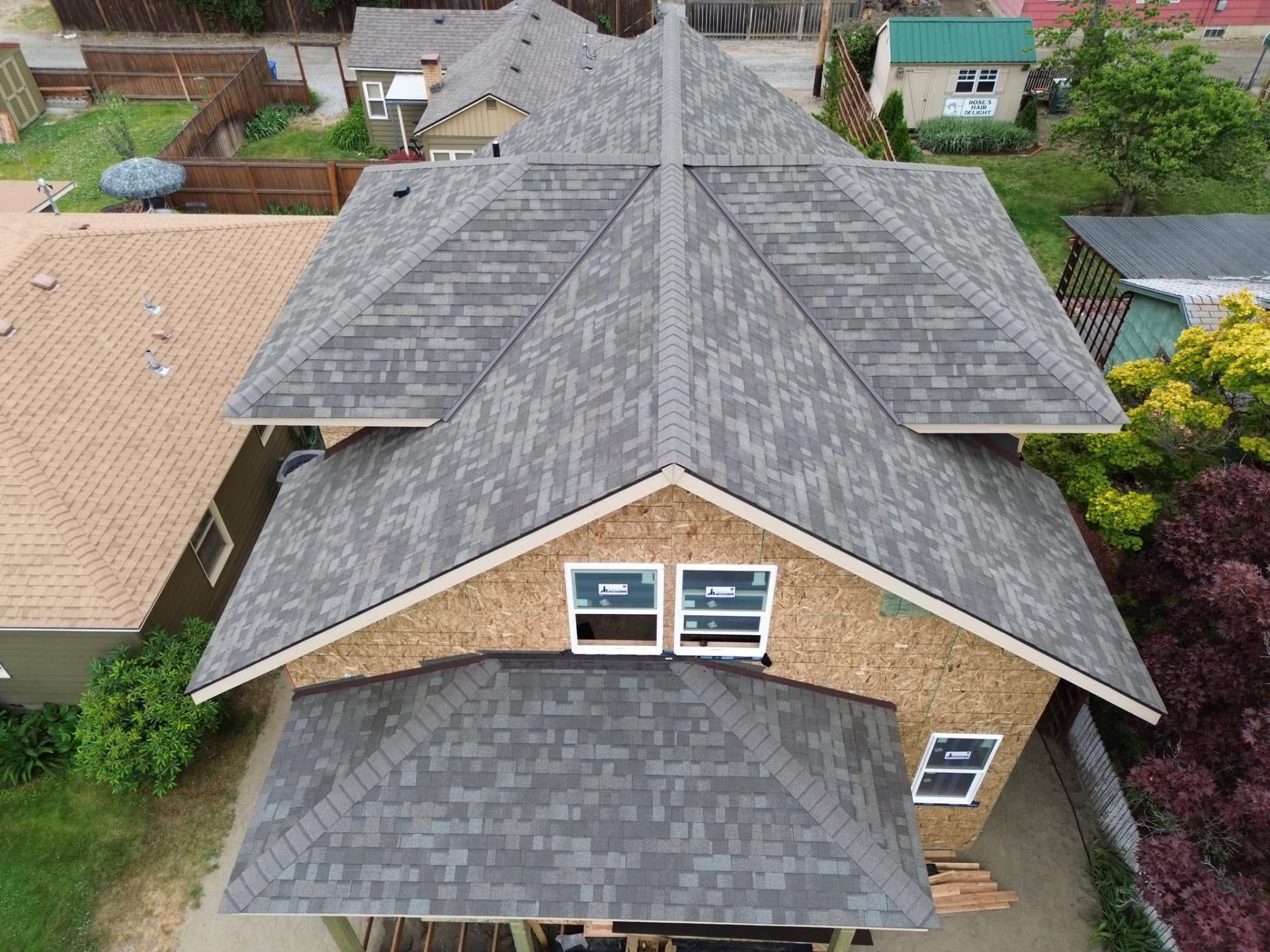 Completed gray shingle roof on a brick house