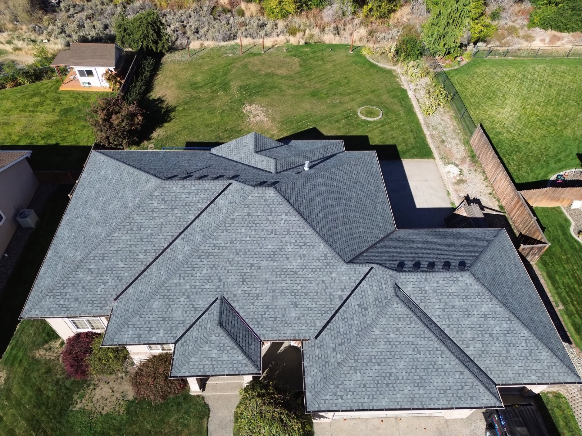 Drone view of a finished gray architectural shingle roof with clean hips and valleys