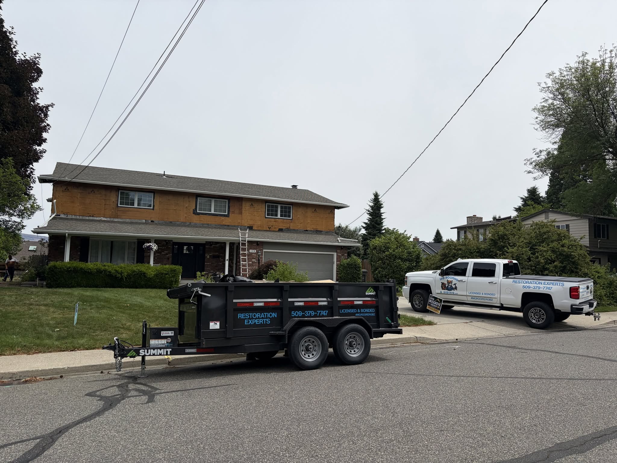 MG Roofing crew truck and dump trailer during roof tear off